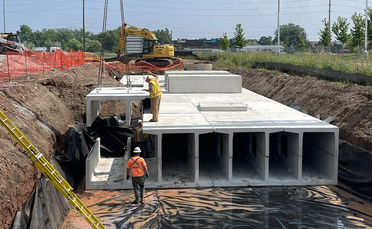 Construction crew guiding a precast concrete DoubleTrap stormwater unit into position at Walkers Line Corporate Centre Burlington Ontario