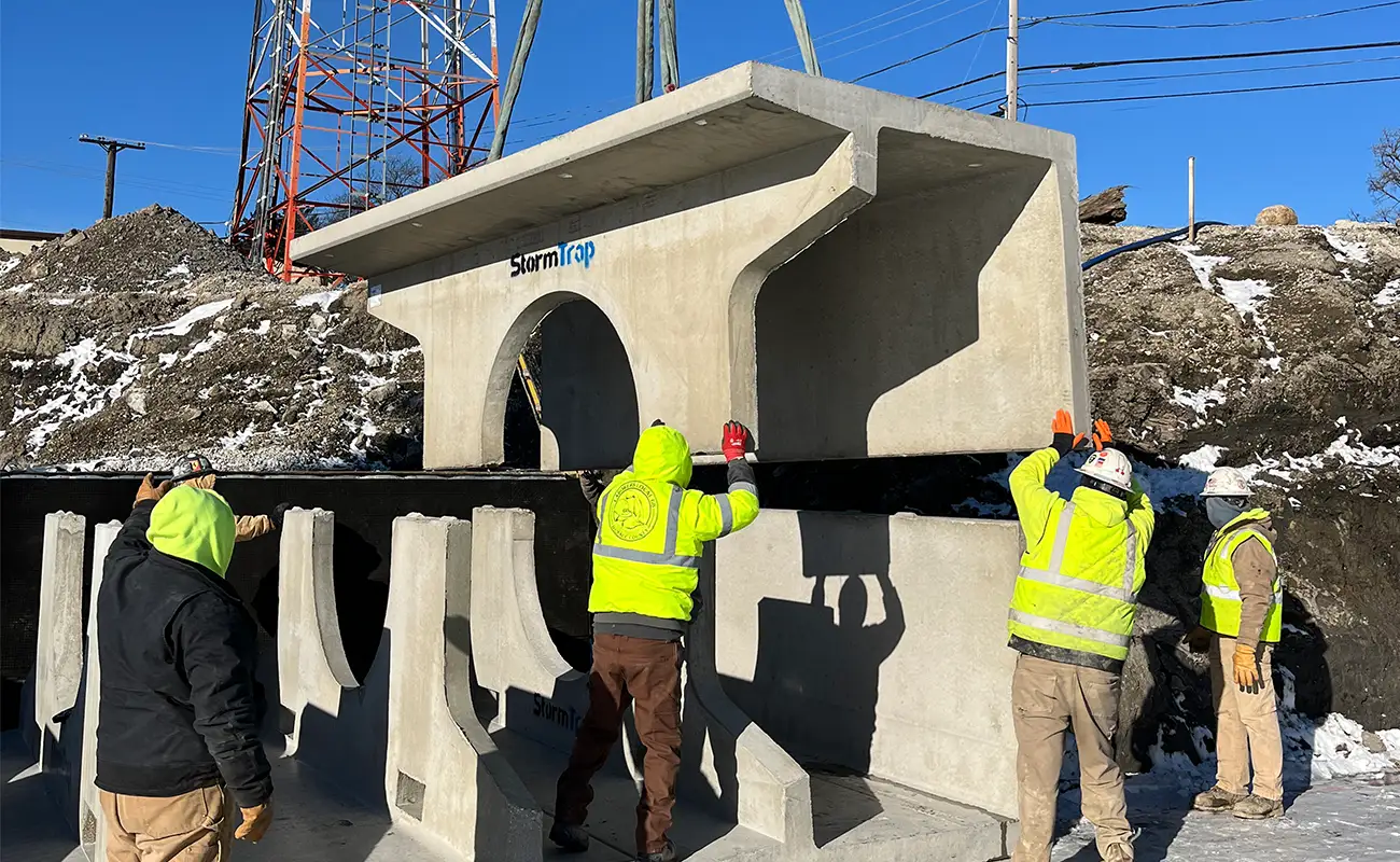 Construction crew guiding StormTrap DoubleTrap precast concrete cap section into position during stormwater detention installation in Oak Lawn, Illinois