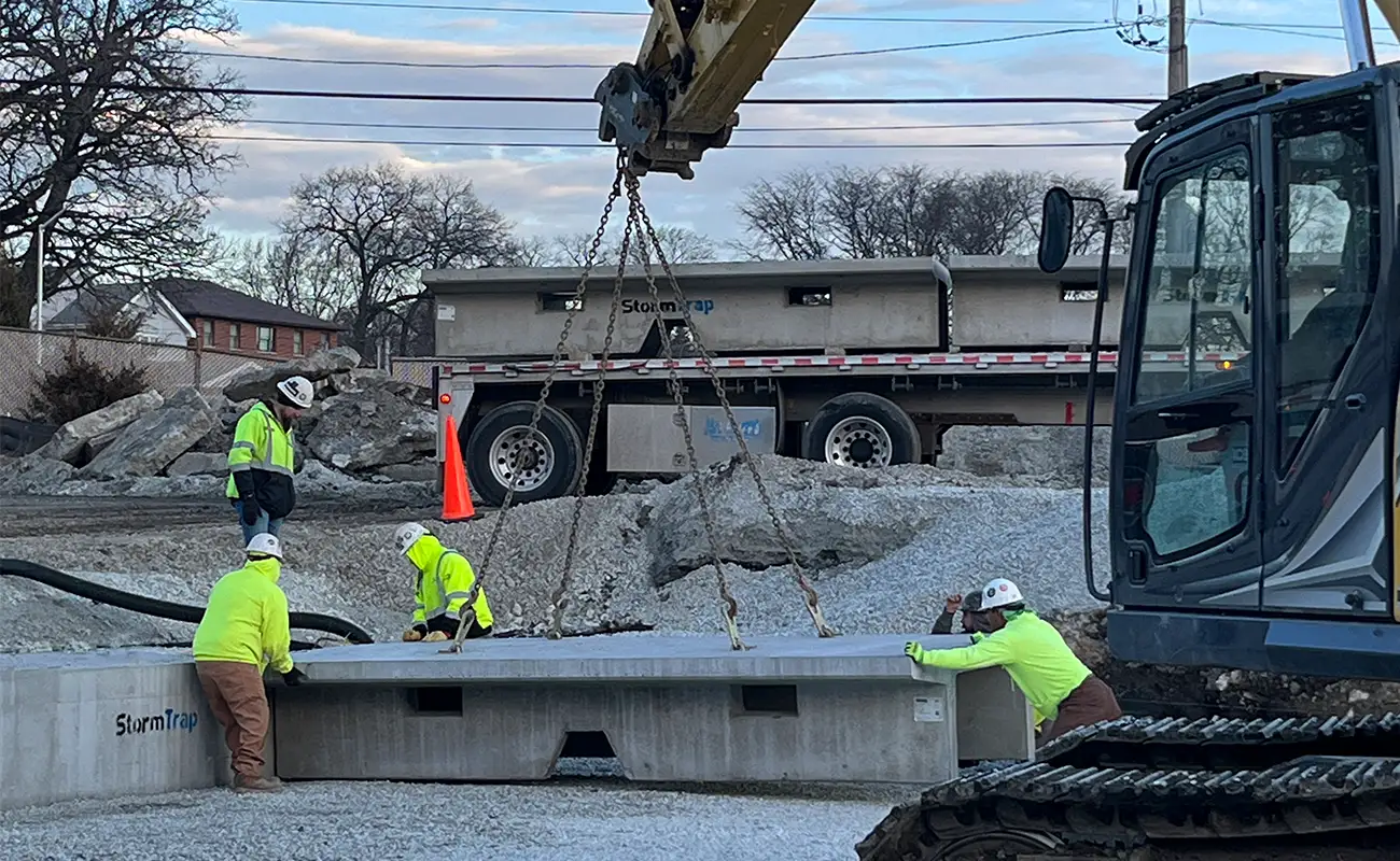 StormTrap precast concrete detention unit being set with an excavator during delivery and installation in Oak Lawn, Illinois