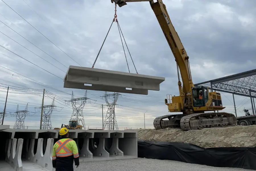 CAT excavator lifting a precast StormTrap DoubleTrap unit into position during installation at Parkhurst Square in Brampton, Ontario