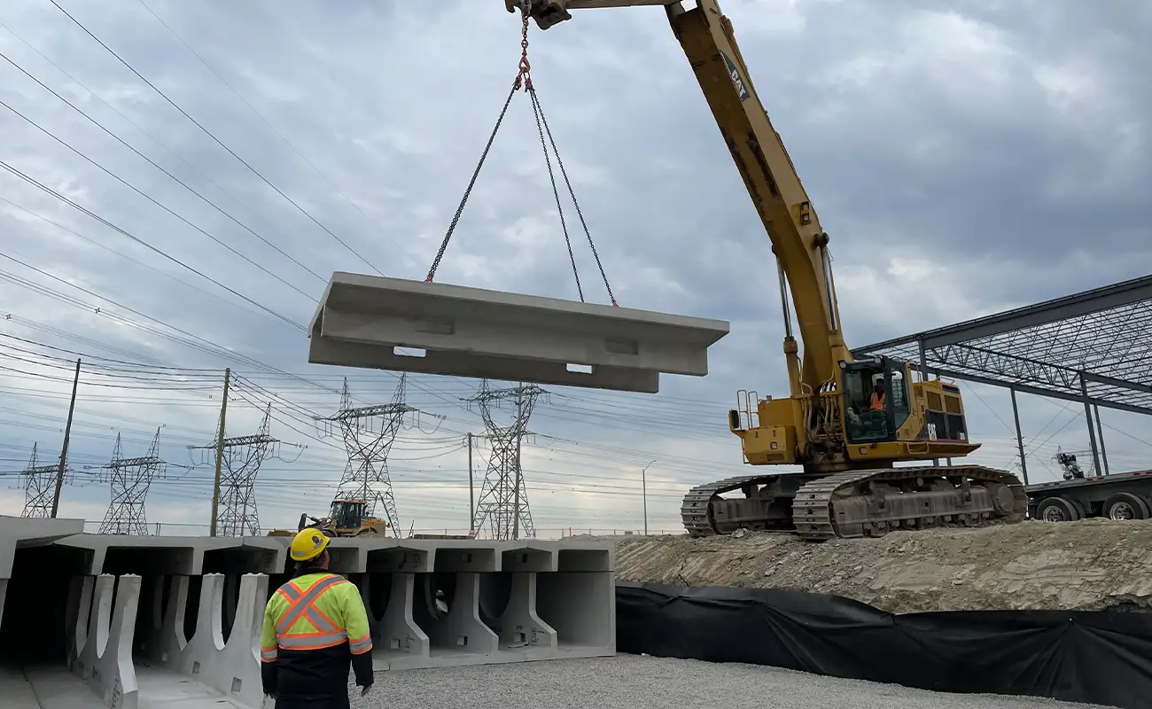 CAT excavator lifting a precast StormTrap DoubleTrap unit into position during installation at Parkhurst Square in Brampton, Ontario