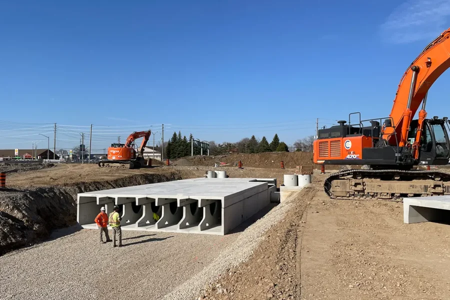 Workers standing beside StormTrap DoubleTrap precast concrete detention units on-site at an industrial warehouse project in Cambridge Ontario