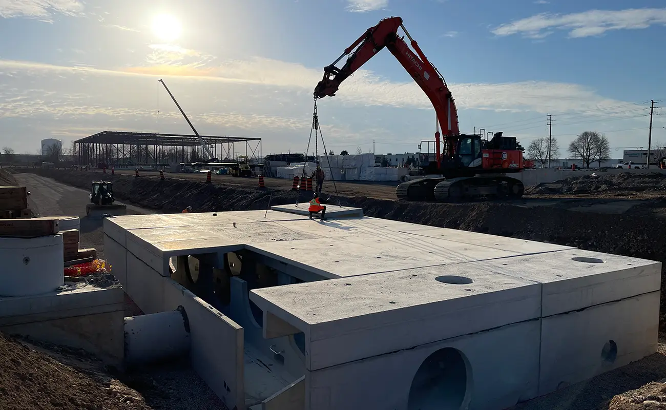 Crane lowering StormTrap DoubleTrap precast concrete slabs into excavation for underground stormwater detention system Cambridge Ontario