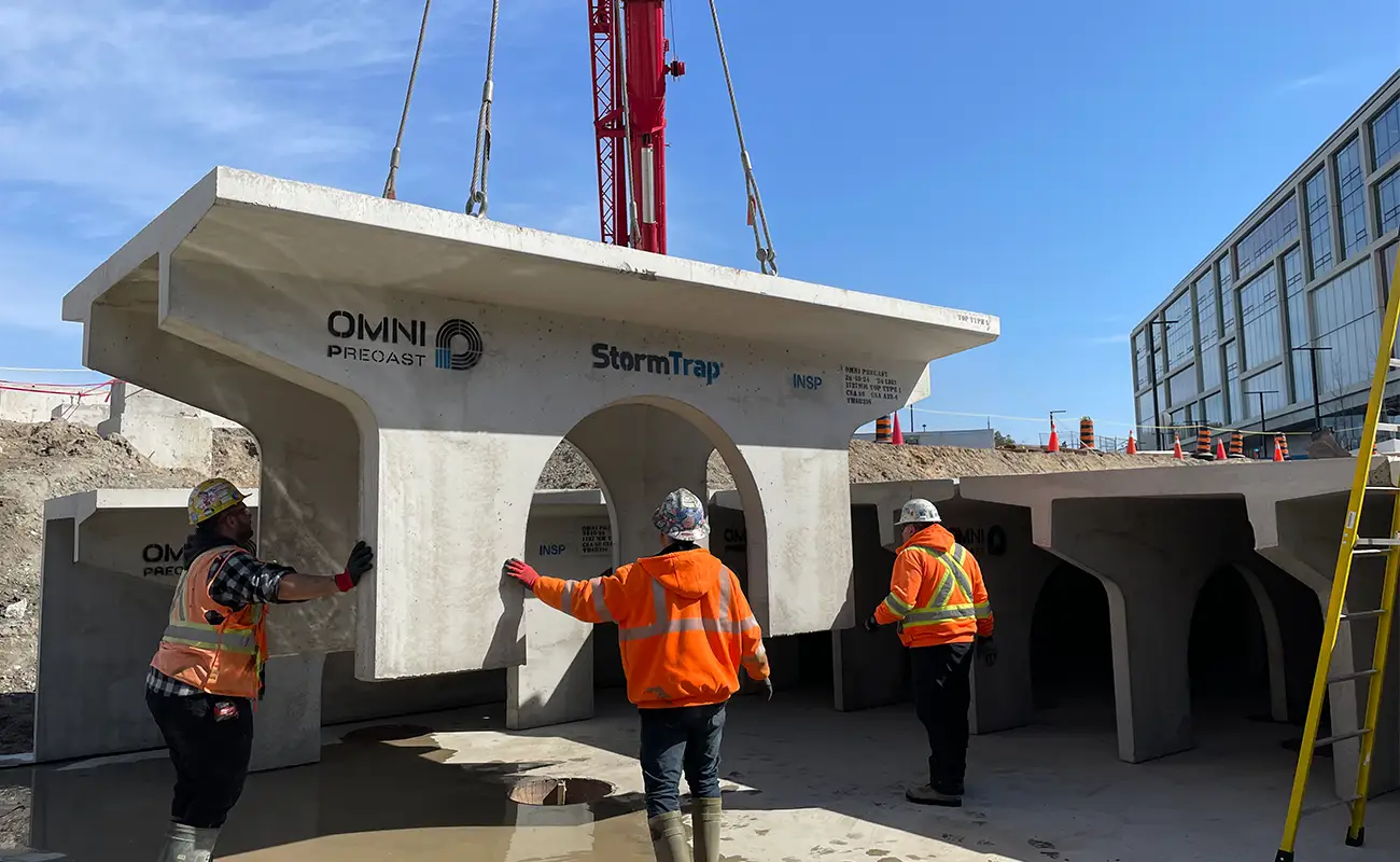 Construction workers guiding a StormTrap SingleTrap precast lowered by crane during installation at the University of Toronto Scarborough