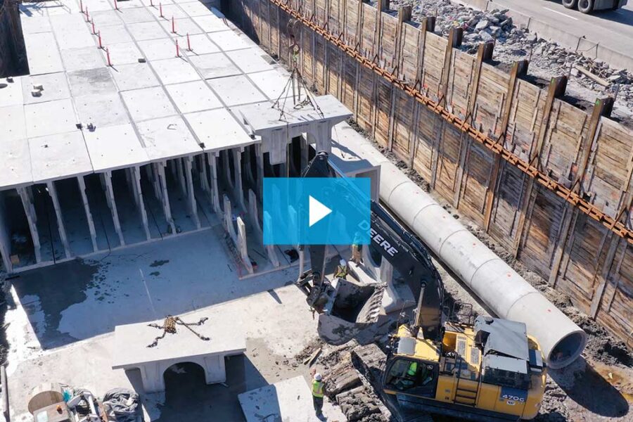A construction site with a large concrete structure, heavy machinery, and workers, surrounded by retaining walls and building materials, showcases the development of a Chicago Stormwater Detention System.