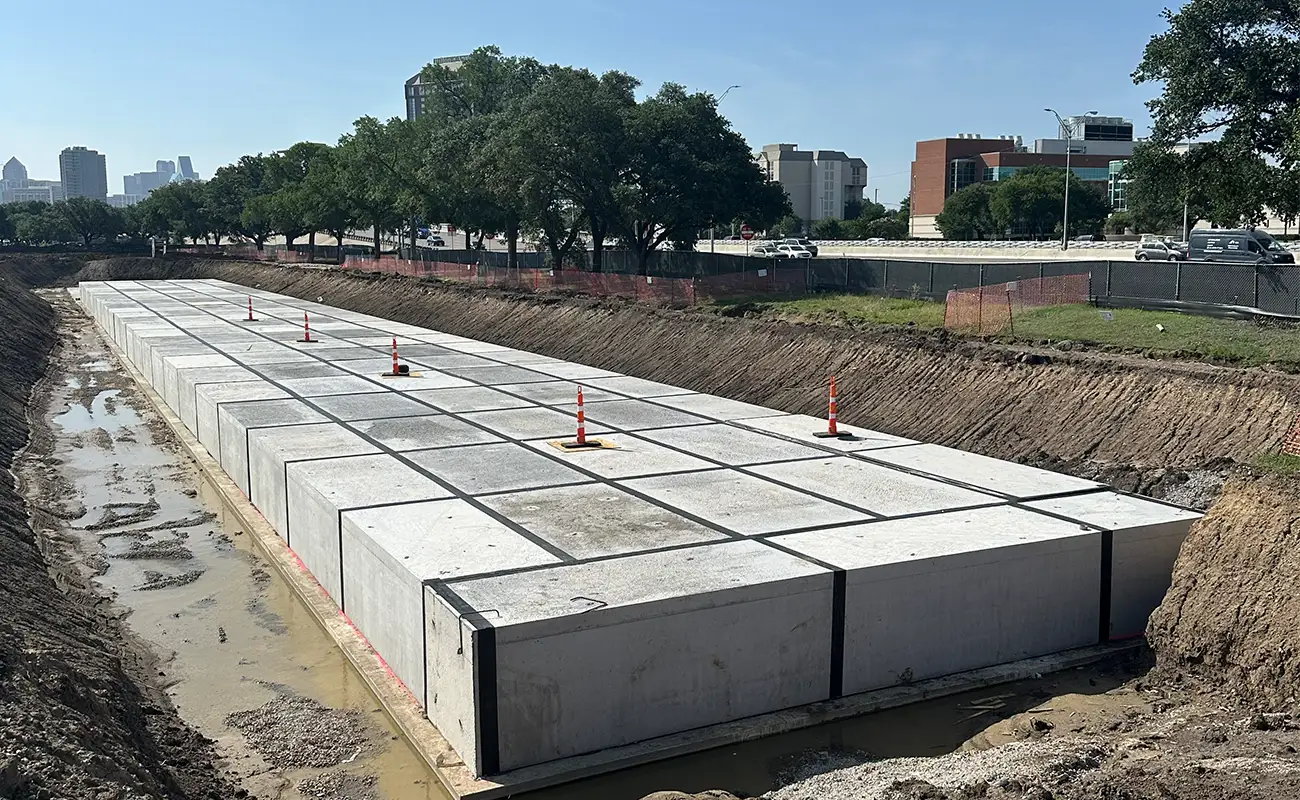 A large, rectangular Crow Market StormTrap detention system installed in a dirt trench, marked with orange traffic cones.