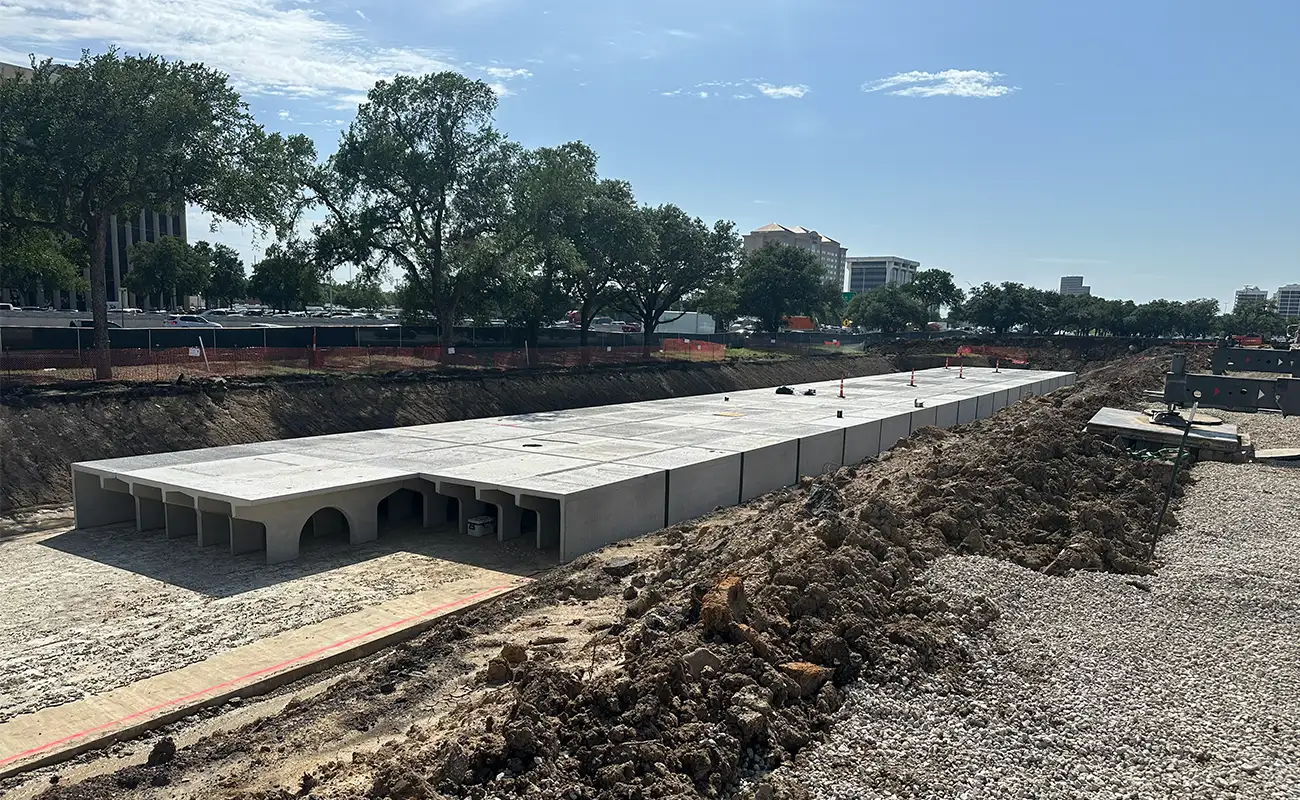 A construction site with a long row of Crow Market StormTrap detention system culvert segments installed in a trench.